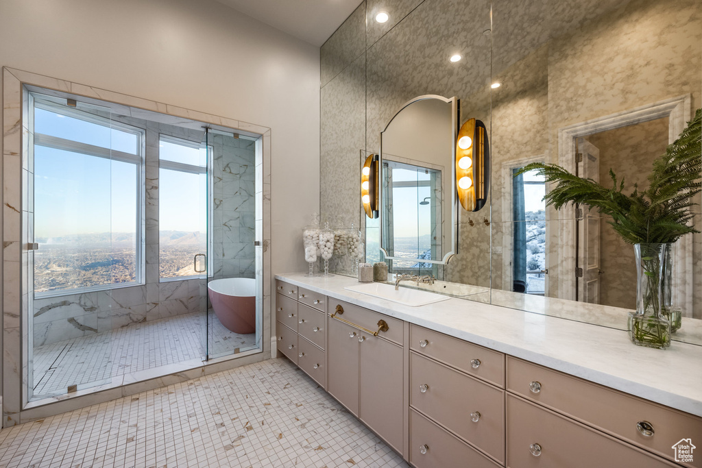 Bathroom with tile patterned floors, plenty of natural light, shower with separate bathtub, and vanity
