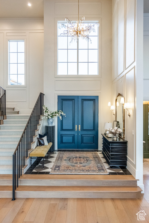 Foyer featuring a high ceiling, a chandelier, stairs, and hardwood / wood-style flooring