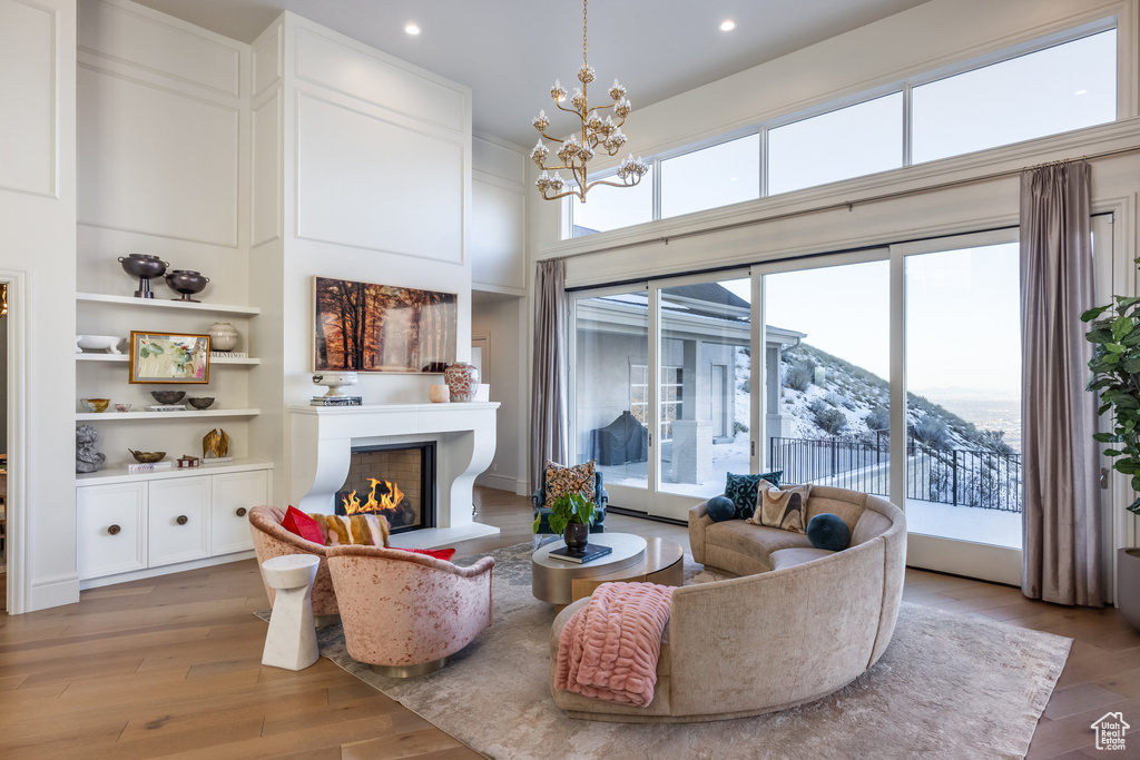 Living room featuring light hardwood / wood-style flooring, built in features, a notable chandelier, a mountain view, and a towering ceiling