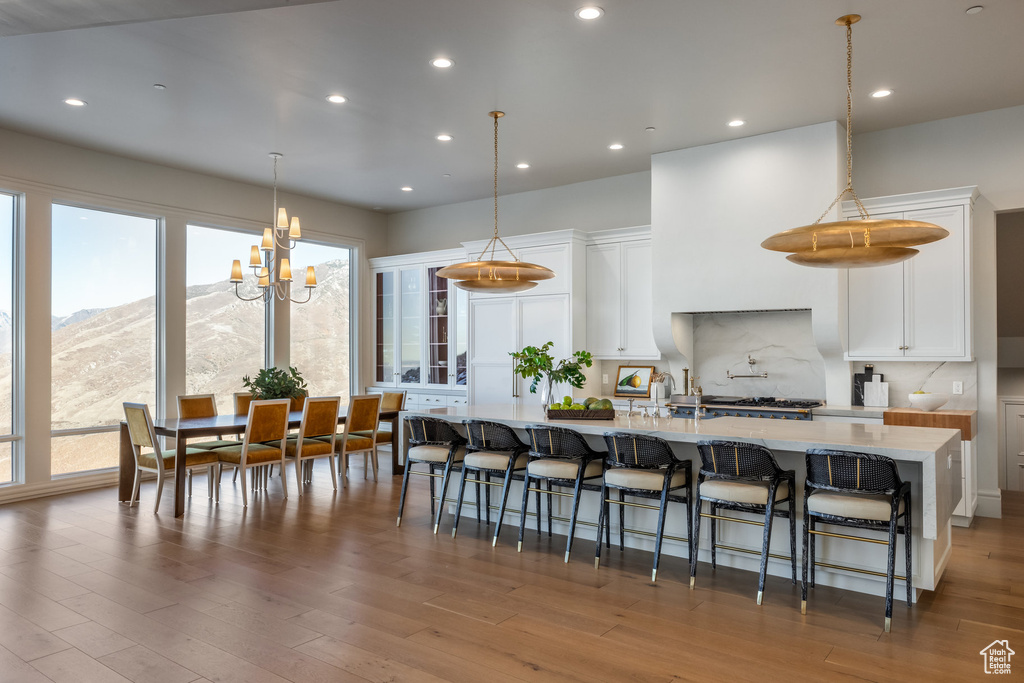 Kitchen with a mountain view, wood-type flooring, decorative light fixtures, and white cabinets