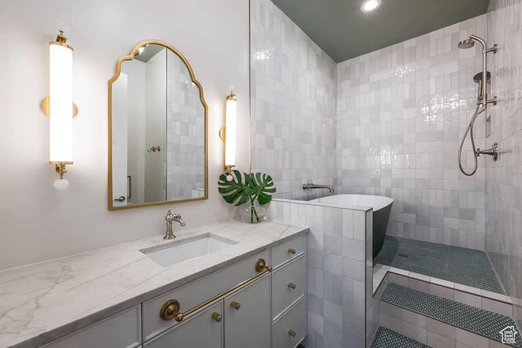 Bathroom featuring vanity, shower with separate bathtub, and tile walls