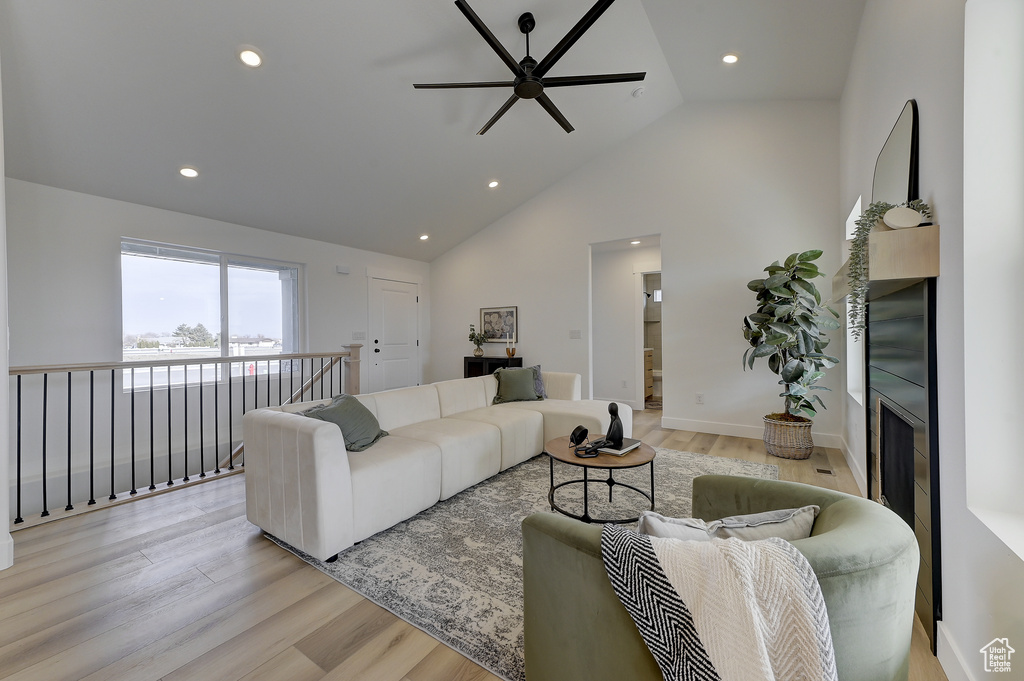 Living room with ceiling fan, high vaulted ceiling, and light wood-type flooring