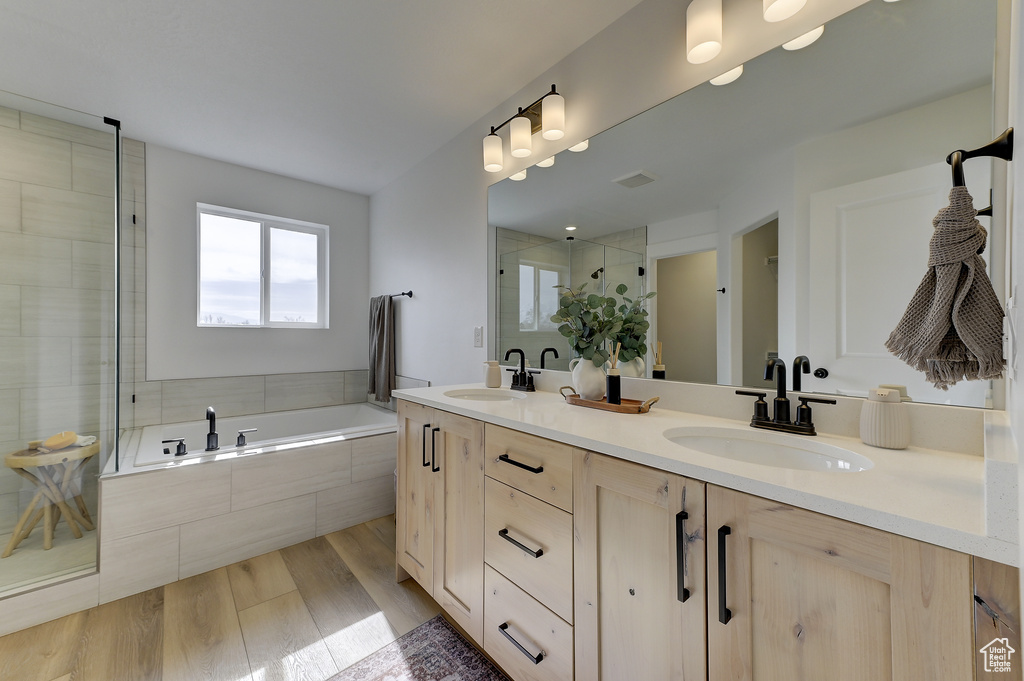 Bathroom featuring wood-type flooring, plus walk in shower, and vanity