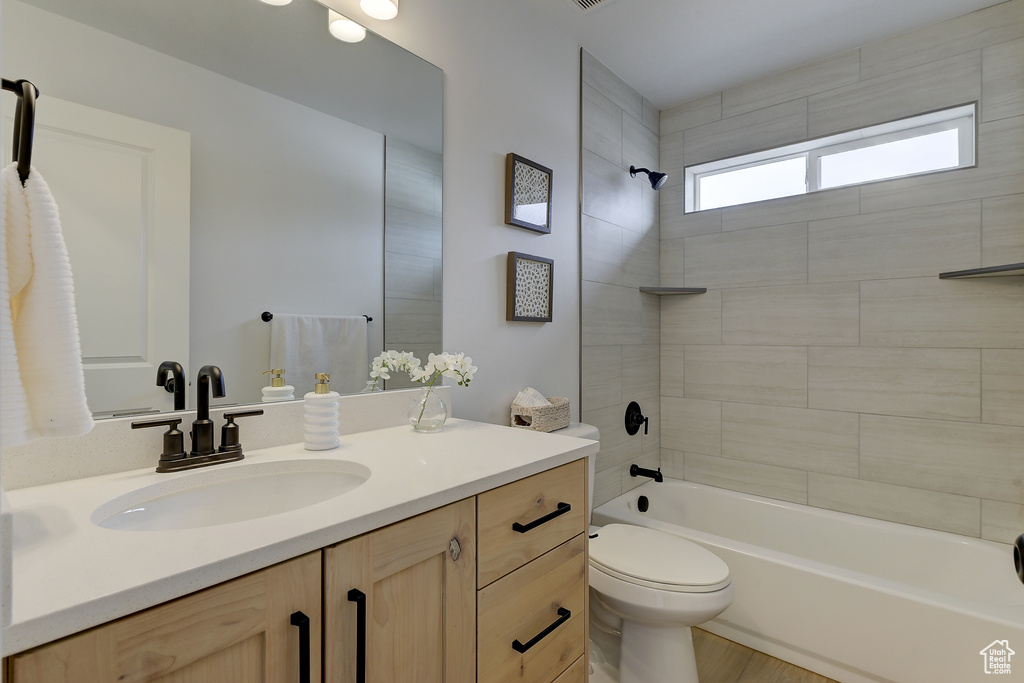 Full bathroom featuring tiled shower / bath combo, vanity, and toilet