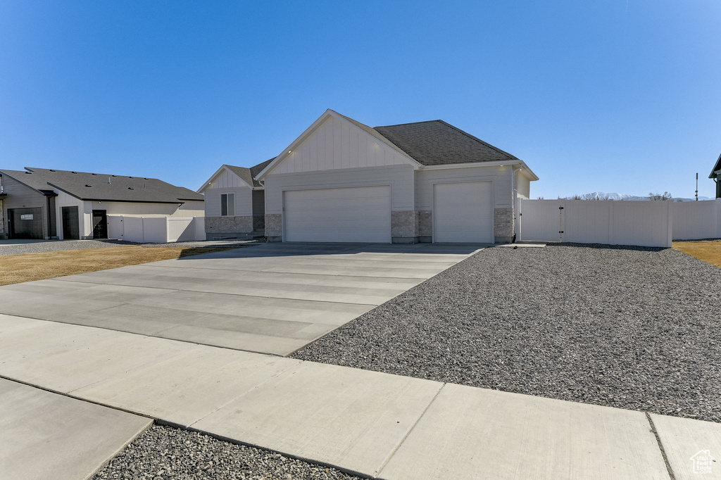 View of front of property with a garage, driveway, a gate, fence, and board and batten siding