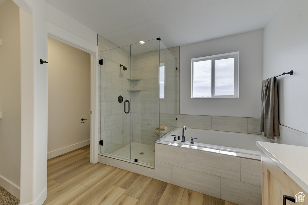 Bathroom featuring vanity, wood-type flooring, and separate shower and tub