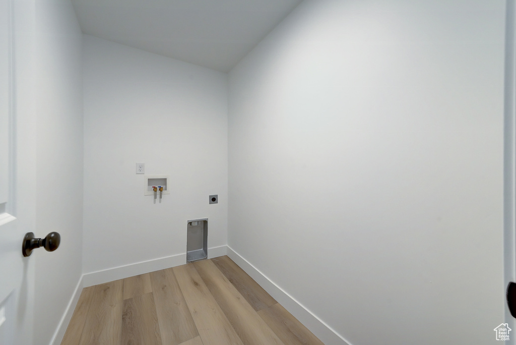 Clothes washing area with hookup for a washing machine, electric dryer hookup, and light wood-type flooring