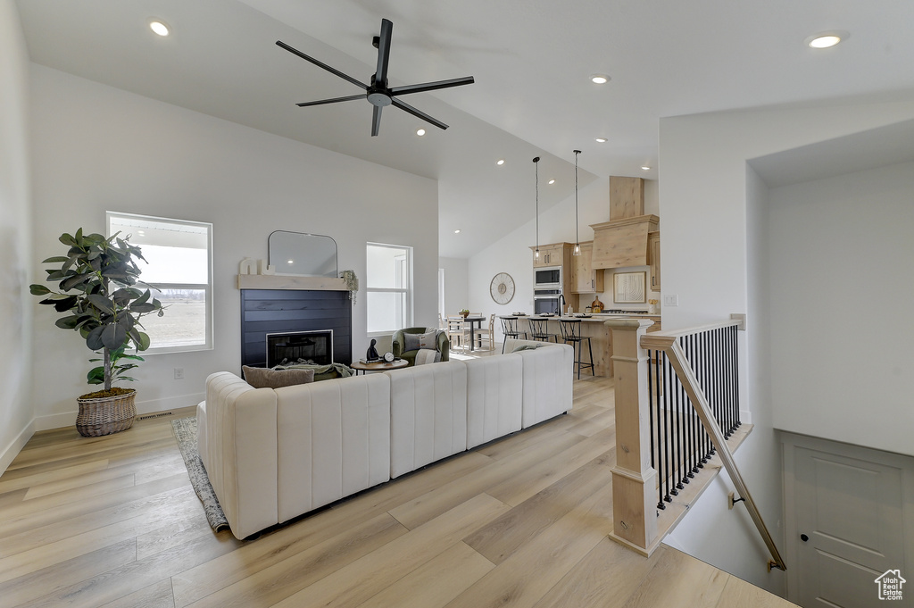 Living room featuring ceiling fan, high vaulted ceiling, and light hardwood / wood-style floors