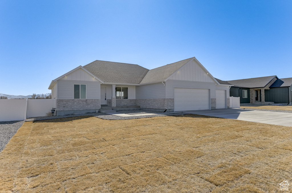 View of front of home with a garage, a shingled roof, fence, concrete driveway, and board and batten siding