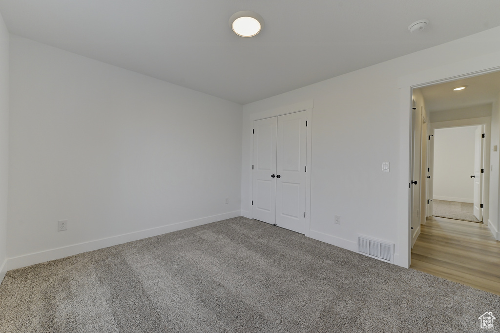 Unfurnished bedroom featuring light carpet and a closet