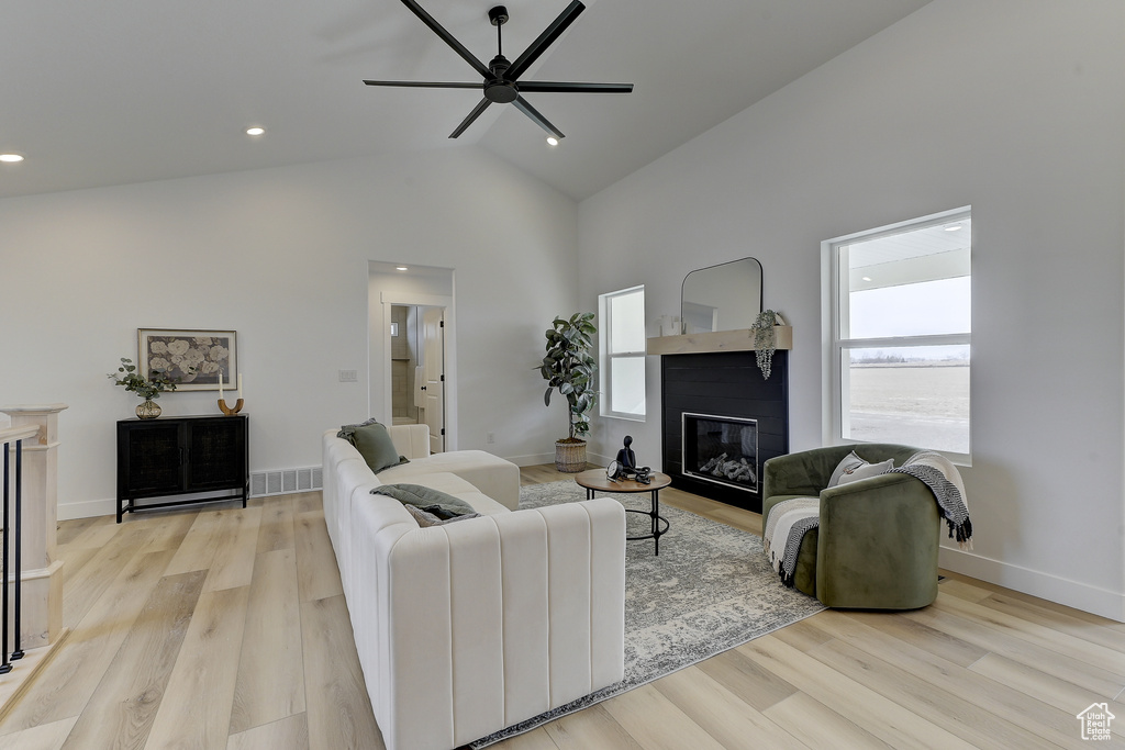 Living room with ceiling fan, high vaulted ceiling, and light hardwood / wood-style flooring