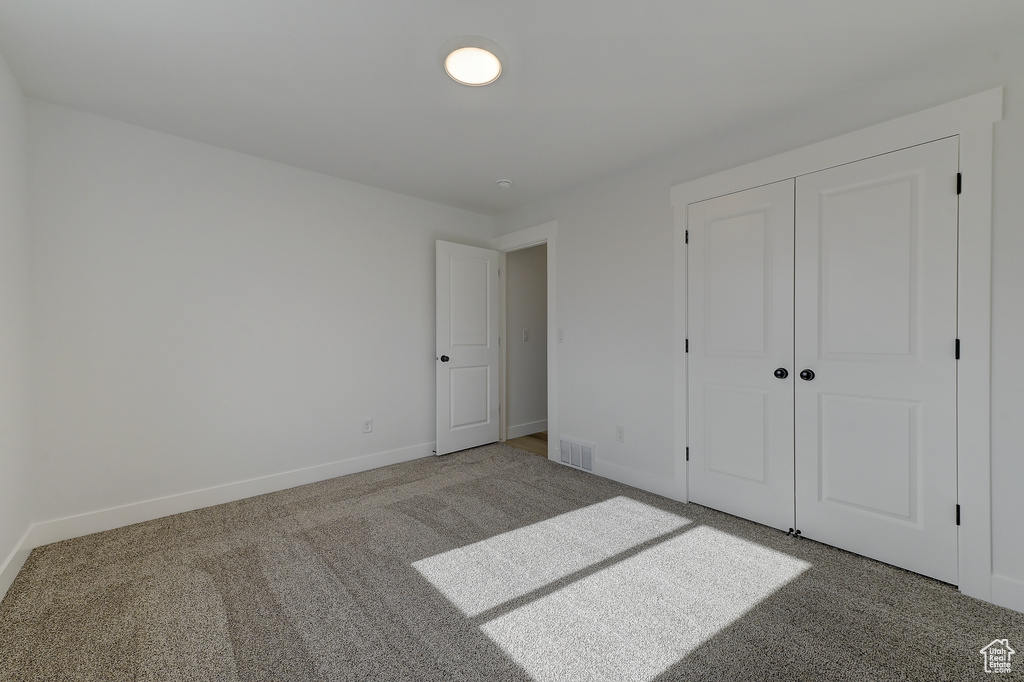 Unfurnished bedroom featuring carpet flooring and a closet