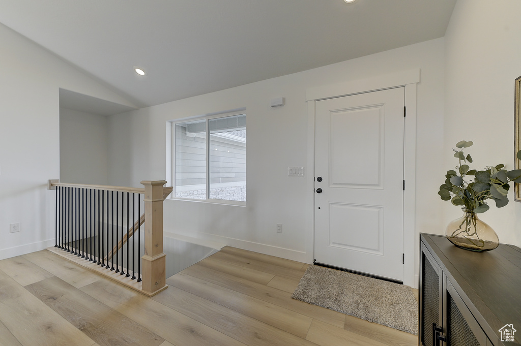 Foyer with vaulted ceiling and light wood-type flooring