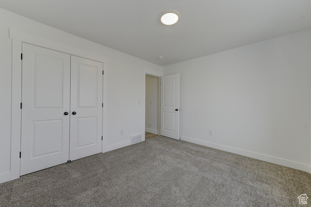 Unfurnished bedroom featuring light colored carpet and a closet