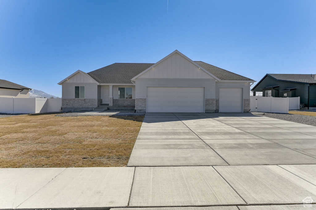 View of front of home with board and batten siding, fence, driveway, and an attached garage