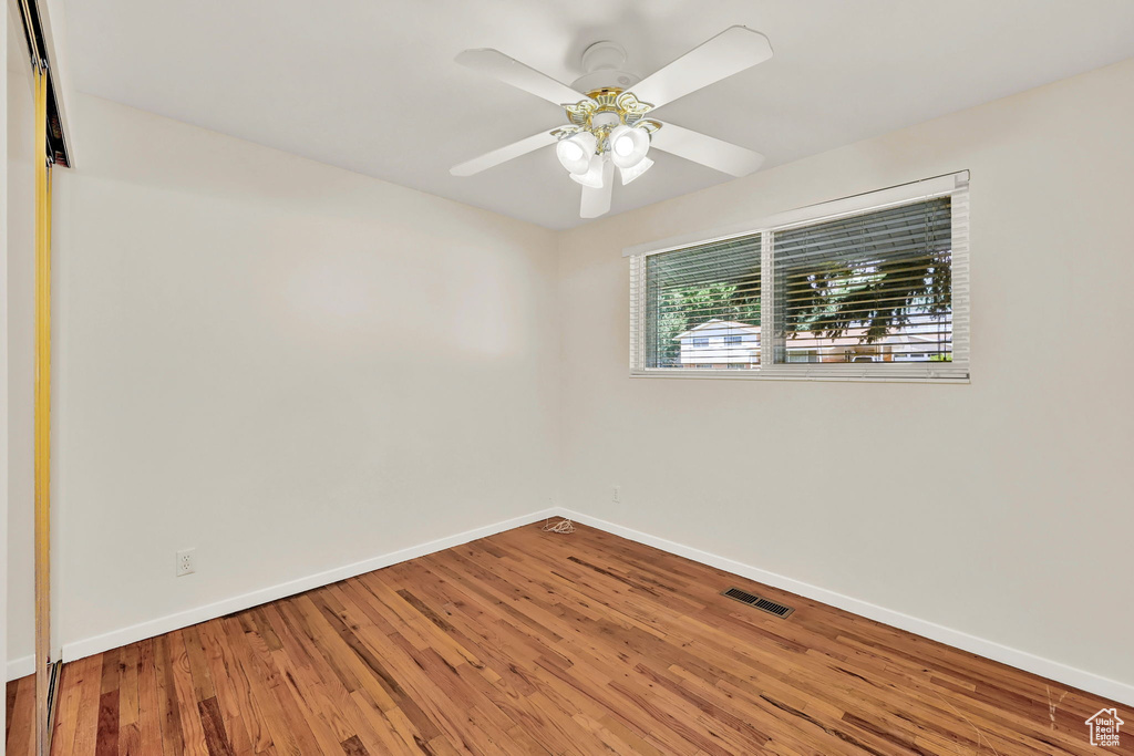 Spare room with baseboards, wood finished floors, and a ceiling fan