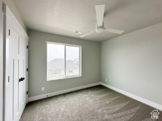 Unfurnished bedroom featuring ceiling fan, carpet floors, and baseboards