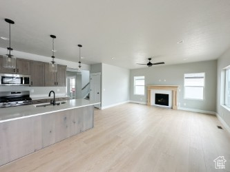 Kitchen with appliances with stainless steel finishes, light countertops, open floor plan, and decorative light fixtures