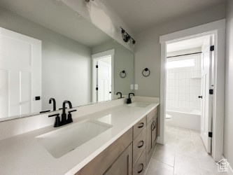 Bathroom with tile patterned floors, a sink, shower / bathtub combination, and double vanity