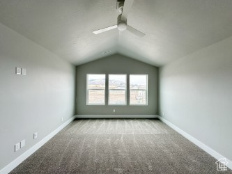 Unfurnished room featuring lofted ceiling, ceiling fan, baseboards, and carpet flooring