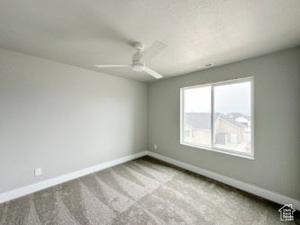 Unfurnished room with a ceiling fan, light carpet, and baseboards