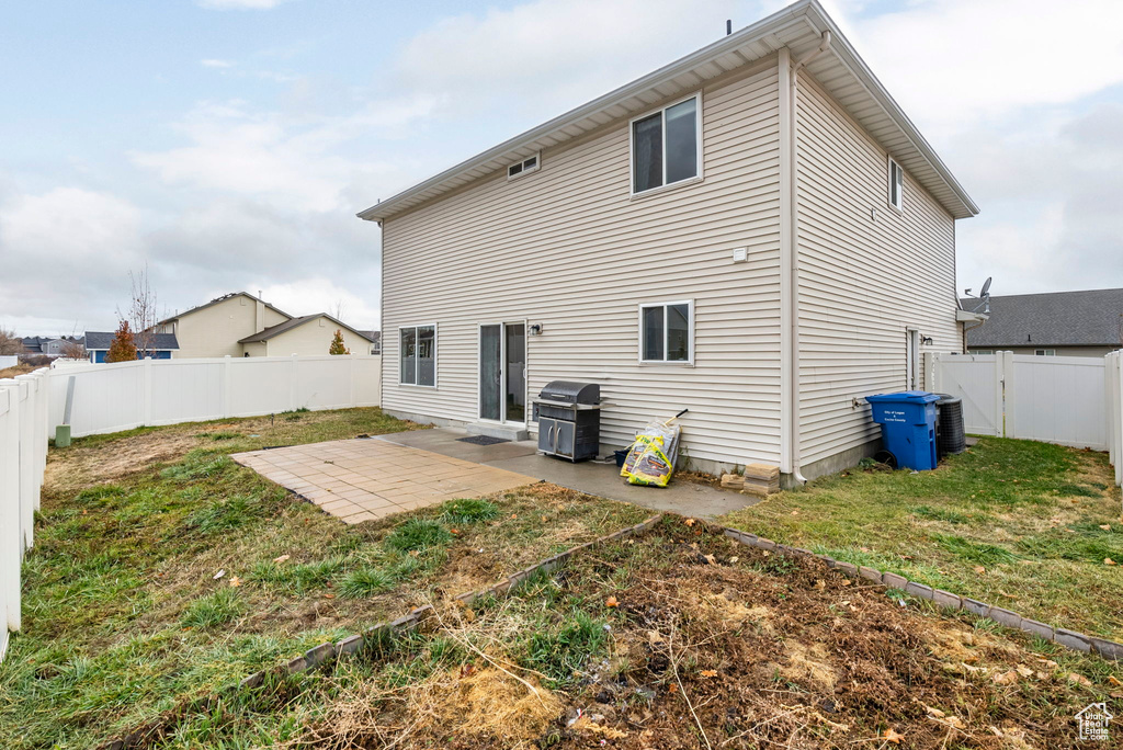 Rear view of property featuring a lawn and a patio area