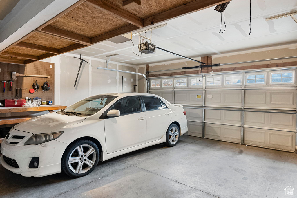 Garage featuring a workshop area, a garage door opener, and a carport
