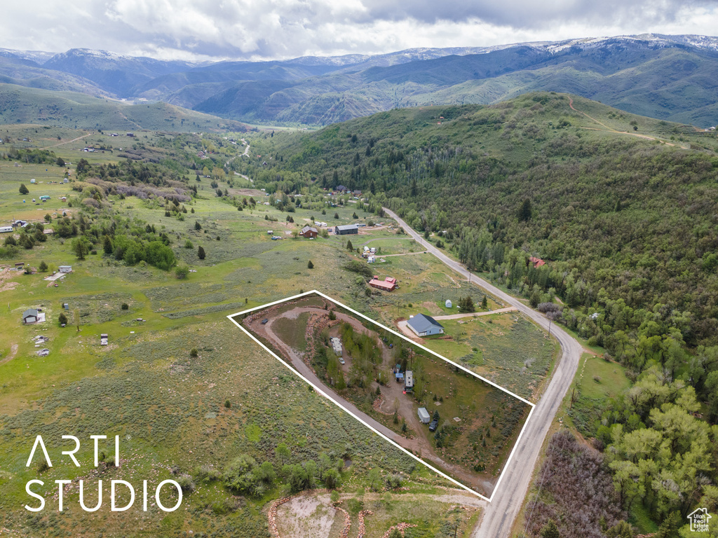 View of rural area with property parcel outlined, a mountain backdrop, and a forest