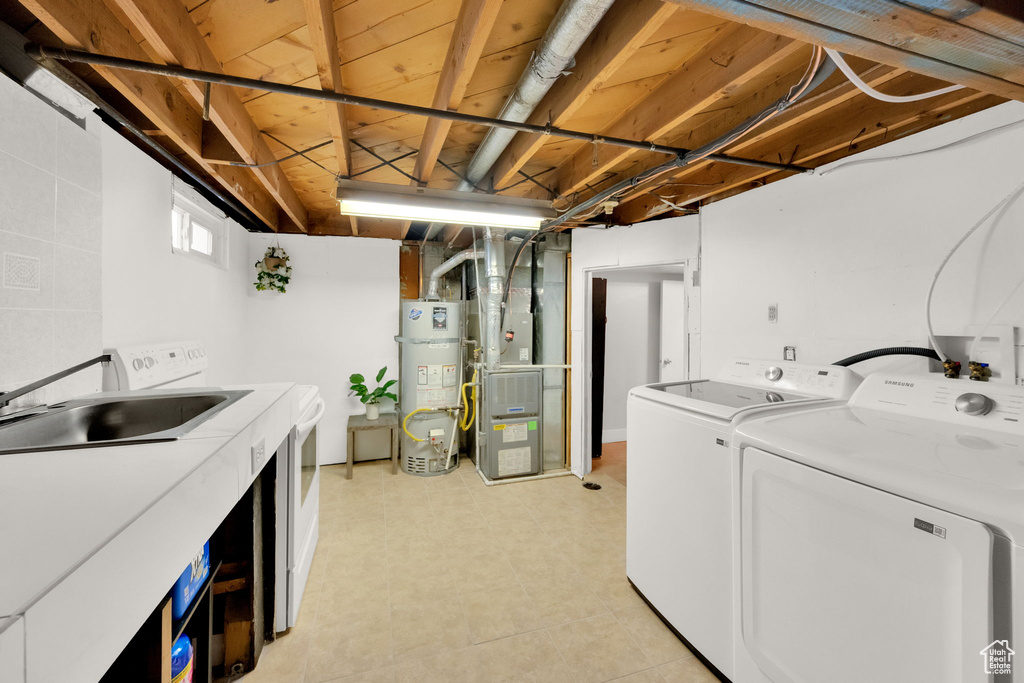 Washroom with washing machine and clothes dryer, strapped water heater, and heating unit