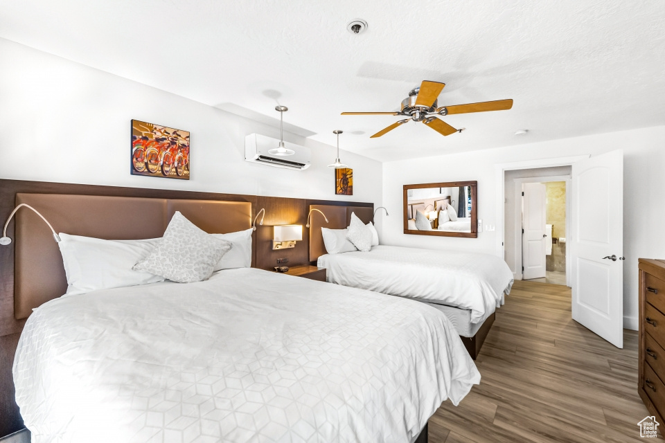 Bedroom featuring ceiling fan, hardwood / wood-style floors, and a wall mounted air conditioner