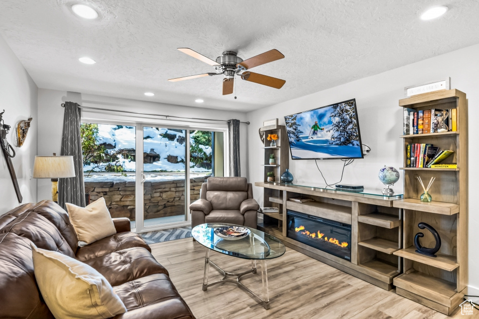 Living room featuring ceiling fan, light hardwood / wood-style floors, and a textured ceiling