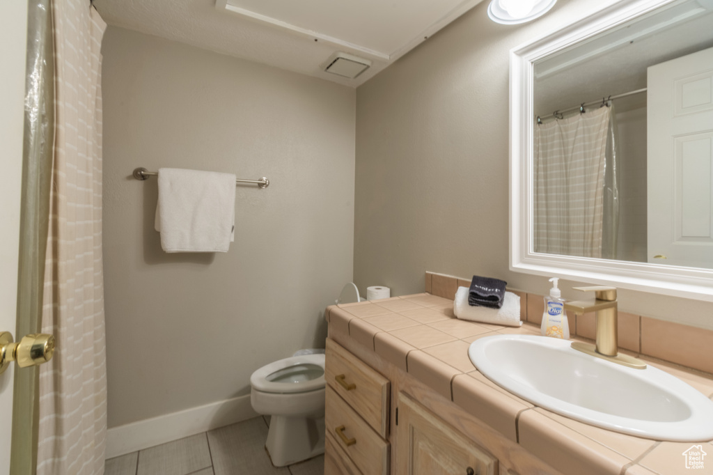 Bathroom featuring tile patterned flooring, vanity, and toilet