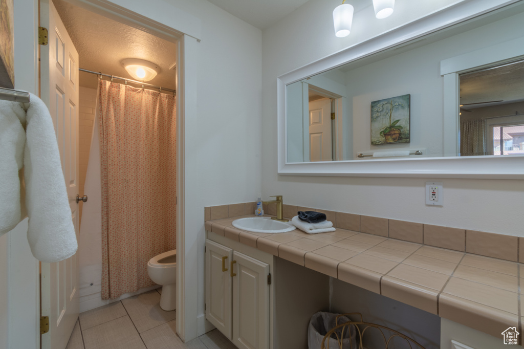 Bathroom with vanity, tile patterned flooring, ceiling fan, toilet, and walk in shower