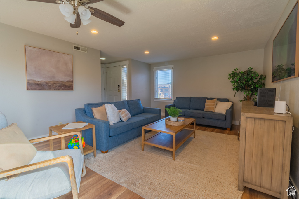 Living room with ceiling fan and light hardwood / wood-style flooring