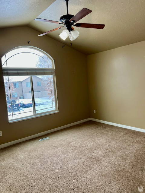 Carpeted empty room featuring ceiling fan, lofted ceiling, and a textured ceiling
