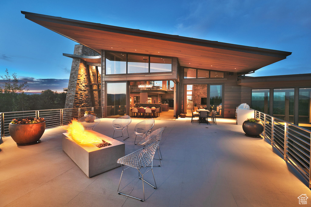 Back of property featuring a fire pit, a patio area, and stone siding