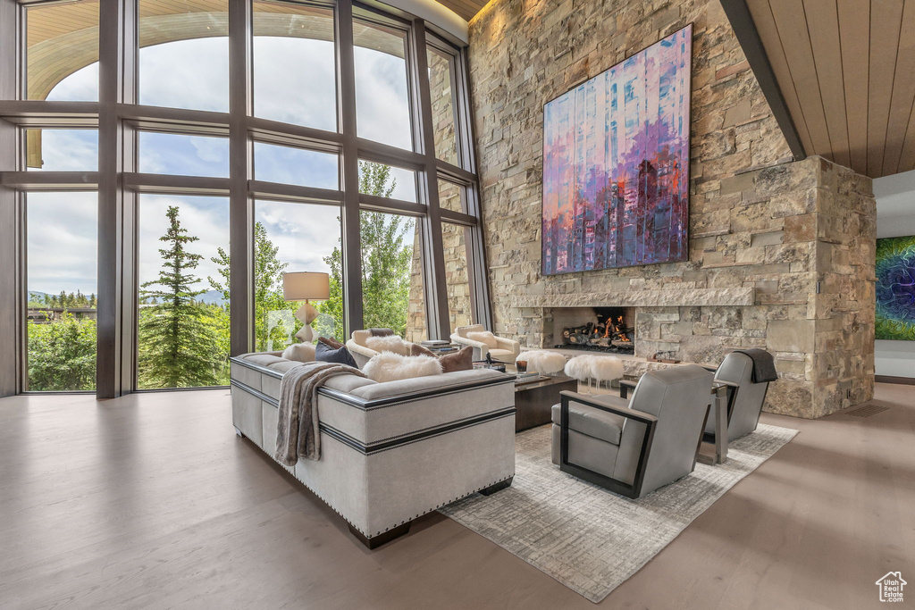 Living room featuring healthy amount of natural light, wood finished floors, wood ceiling, high vaulted ceiling, and a fireplace