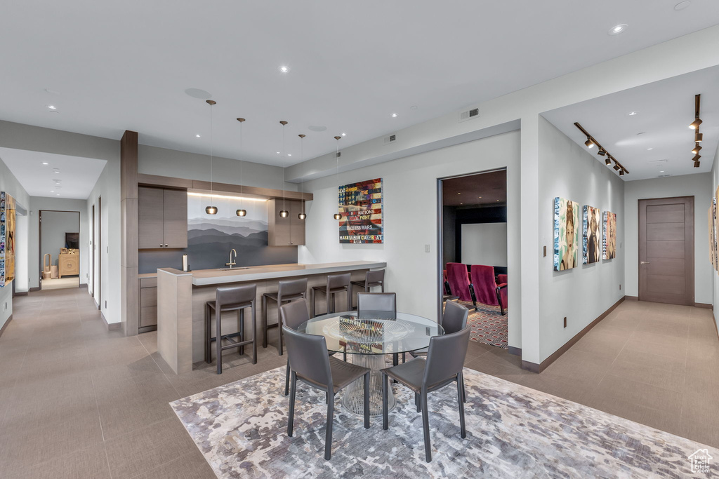 Dining space with light tile patterned floors, recessed lighting, and bar with sink