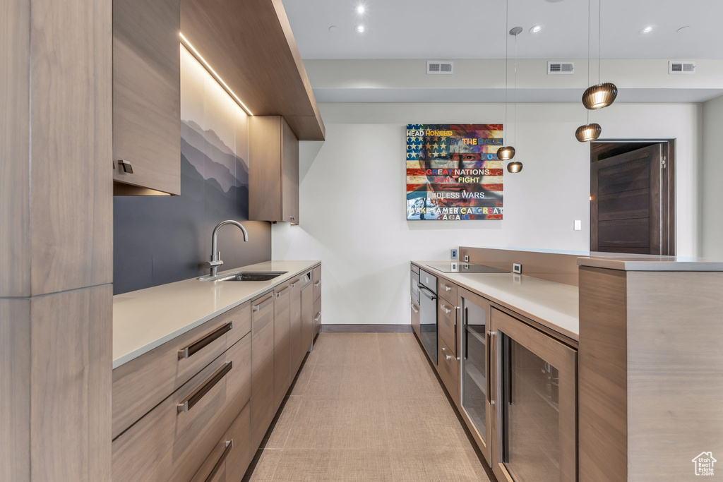 Kitchen with modern cabinets, wine cooler, light countertops, black electric stovetop, and recessed lighting