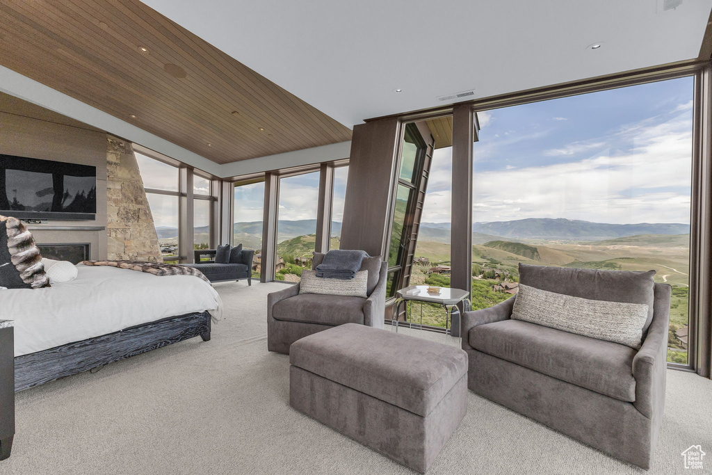 Carpeted bedroom featuring a mountain view, floor to ceiling windows, wooden ceiling, recessed lighting, and a glass covered fireplace