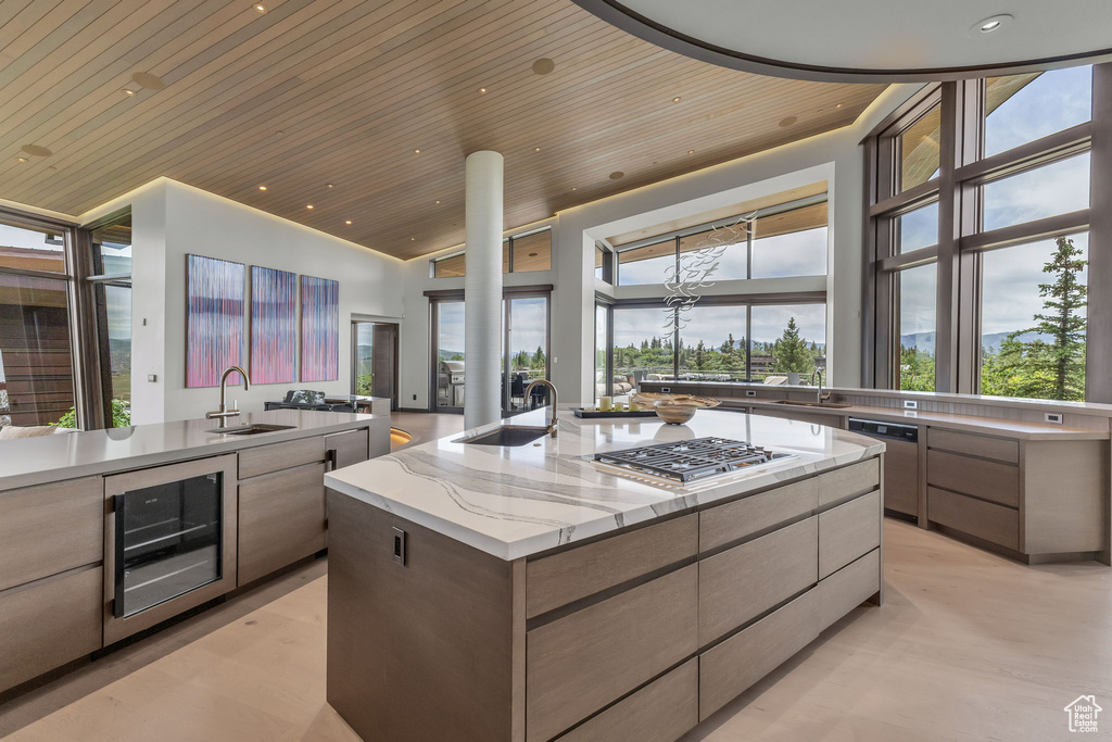 Kitchen featuring wood ceiling, stainless steel appliances, beverage cooler, modern cabinets, and a spacious island
