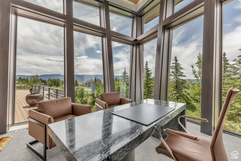 Sunroom featuring a mountain view, carpet flooring, and expansive windows