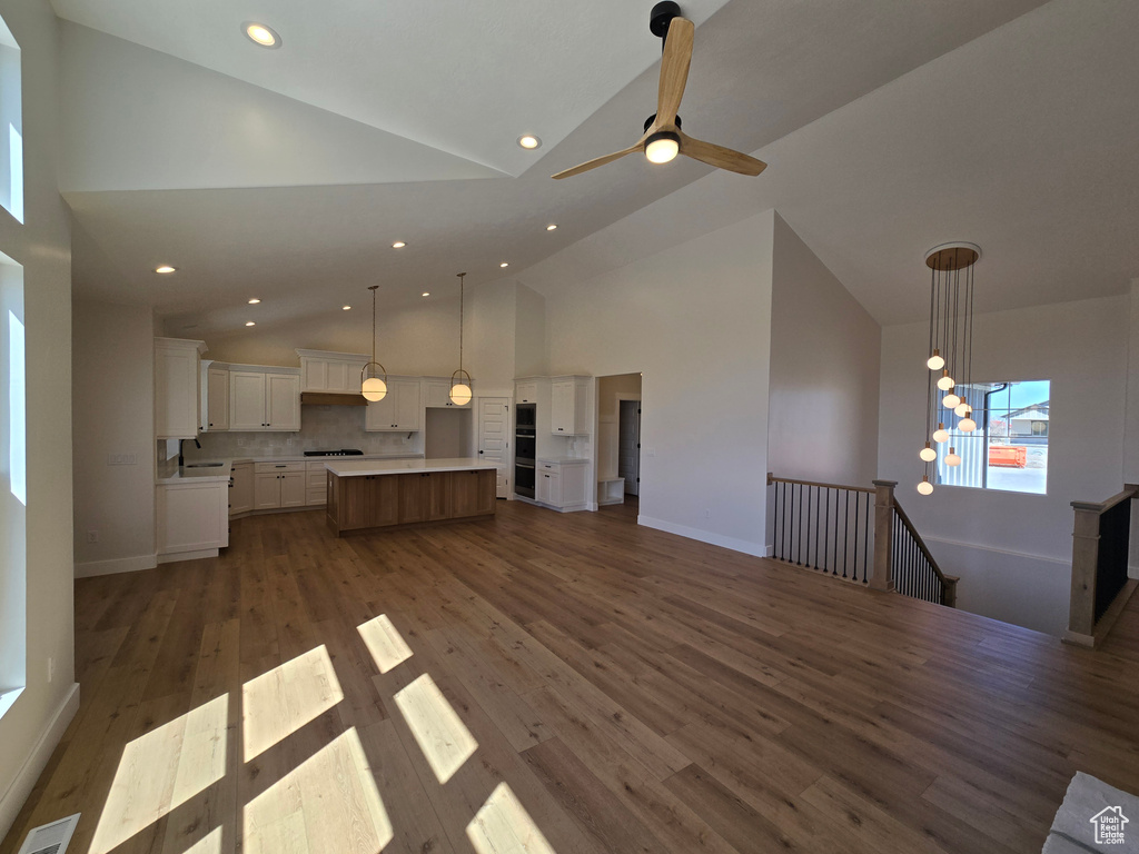 Unfurnished living room with high vaulted ceiling, visible vents, recessed lighting, dark wood-style floors, and baseboards