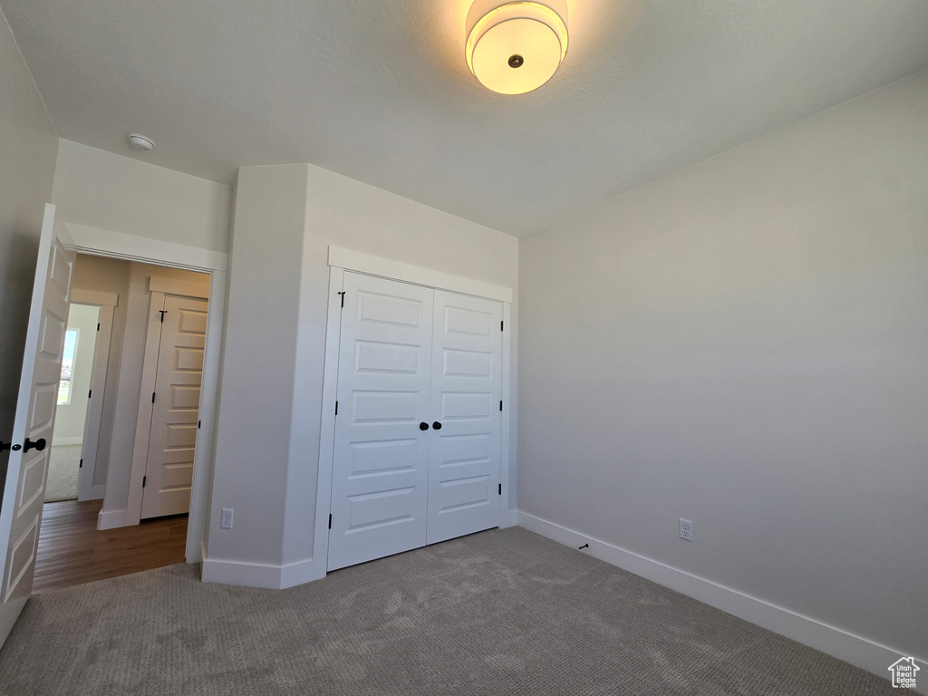 Unfurnished bedroom with carpet flooring, a closet, and baseboards