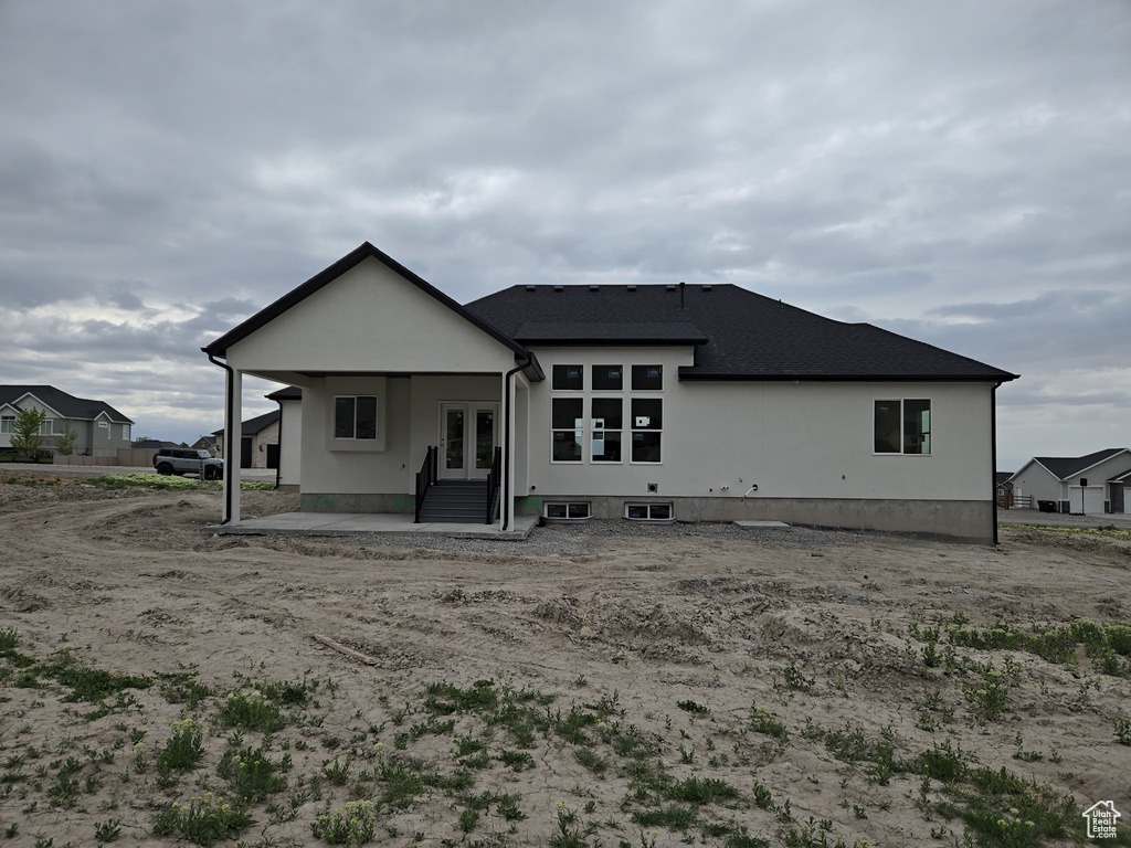 Back of house featuring french doors, a patio, and roof with shingles
