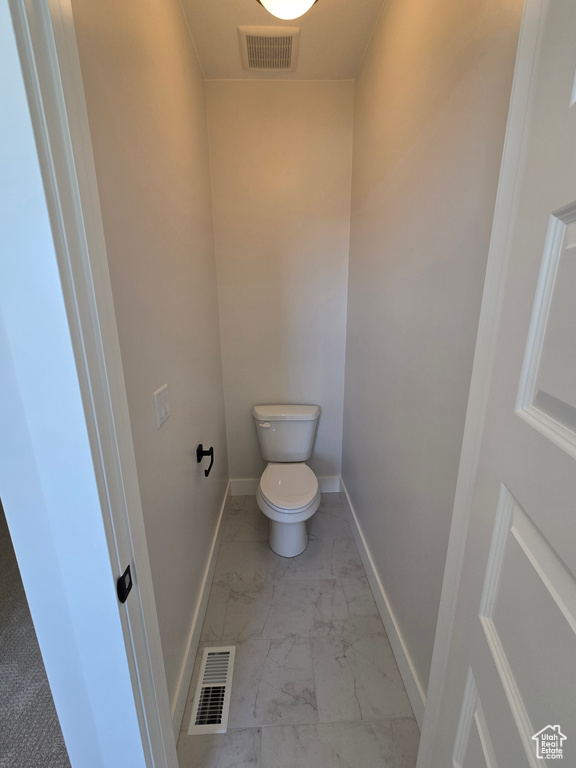 Bathroom with toilet, visible vents, marble finish floor, and baseboards