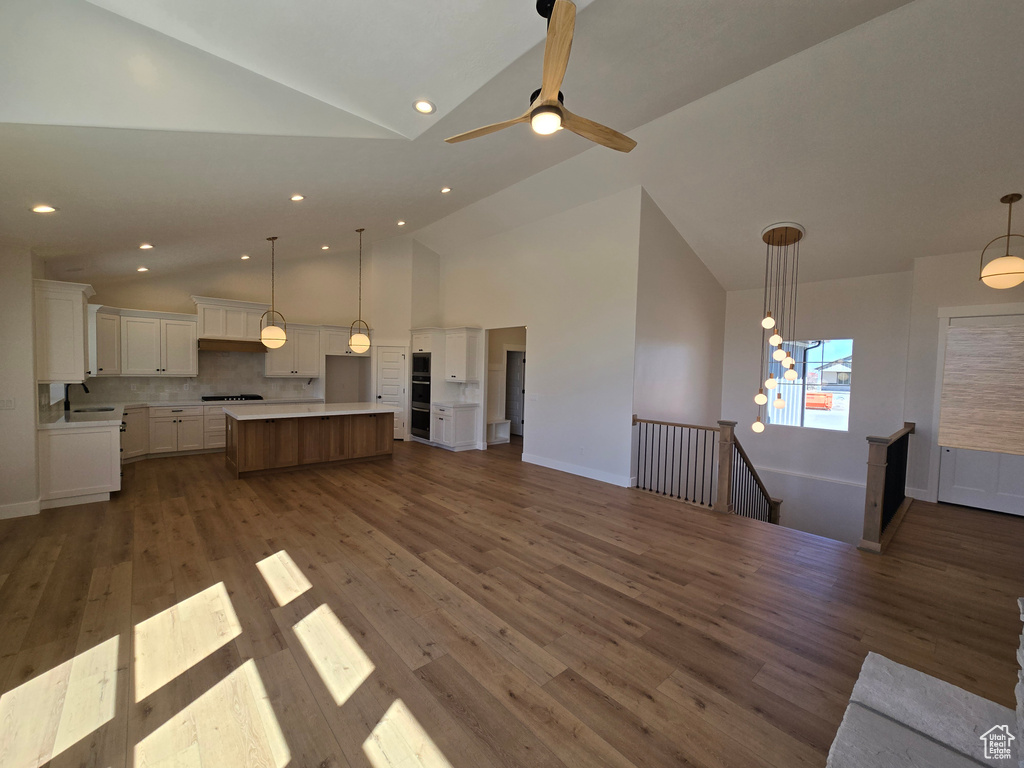 Unfurnished living room featuring recessed lighting, wood finished floors, baseboards, and high vaulted ceiling