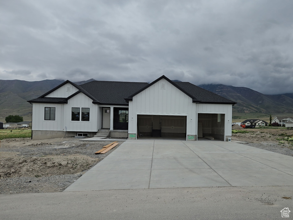 Modern farmhouse featuring a mountain view, a garage, concrete driveway, and board and batten siding