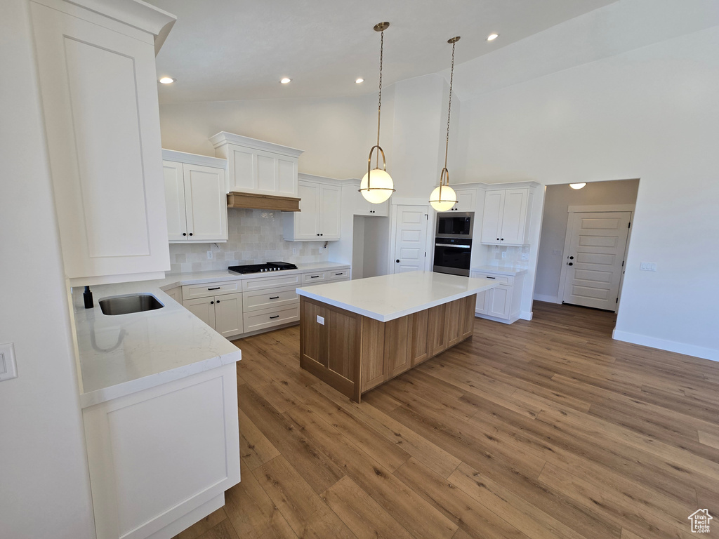 Kitchen with stainless steel microwave, wall oven, black cooktop, and decorative backsplash