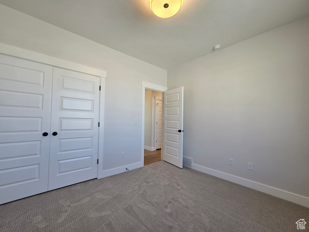 Unfurnished bedroom featuring baseboards, carpet flooring, a closet, and visible vents
